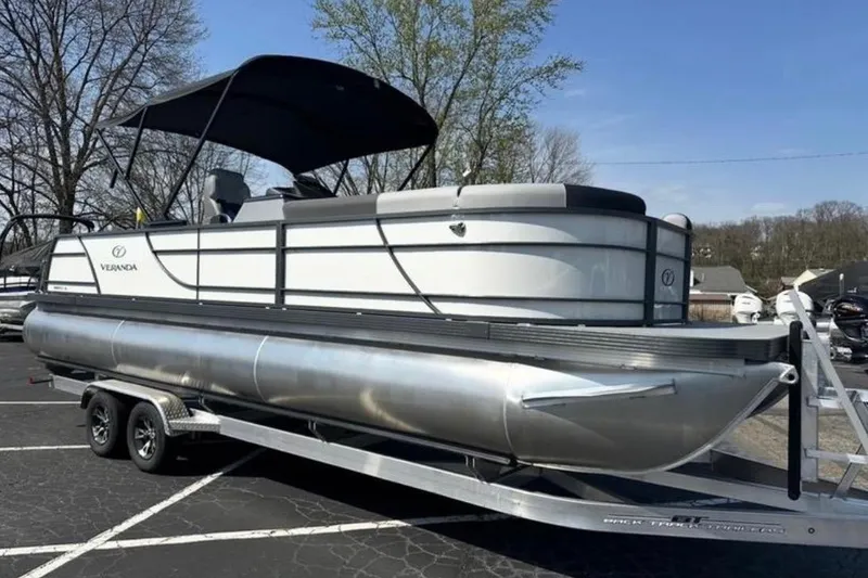 The Image of 2025 Veranda Relax VR25VLC pontoon boat on trailer, parked outdoors. - 1