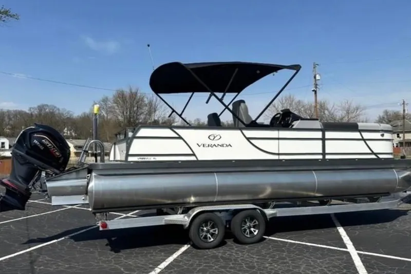 Slide: The Image of 2025 Veranda Relax VR25VLC pontoon boat on trailer, parked outdoors under clear sky. - 5