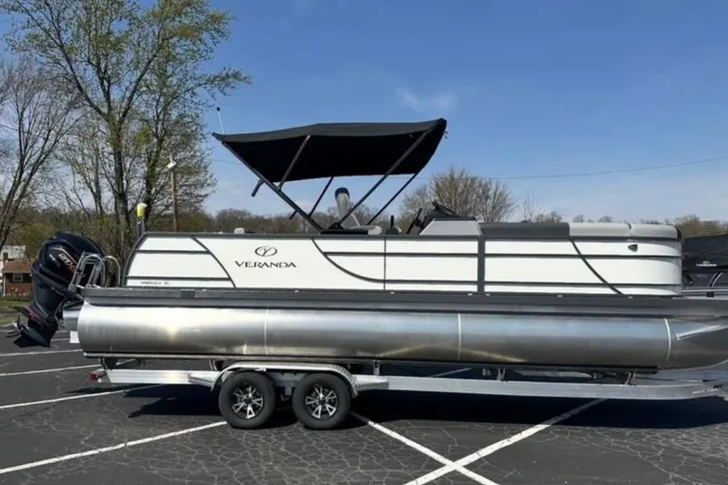 Slide: The Image of 2025 Veranda Relax VR25VLC pontoon boat on trailer, parked outdoors under clear sky. - 8