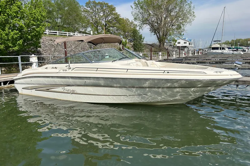 Slide: The Image of 1998 Sea Ray 280 Bow Rider boat docked on calm water, surrounded by greenery. - 13