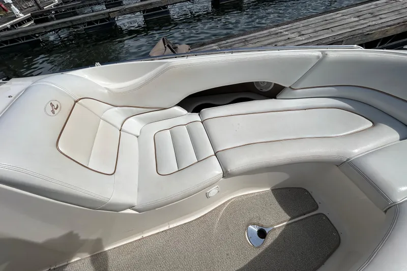 Slide: The Image of 1998 Sea Ray 280 Bow Rider interior seating with white upholstery near dock. - 63