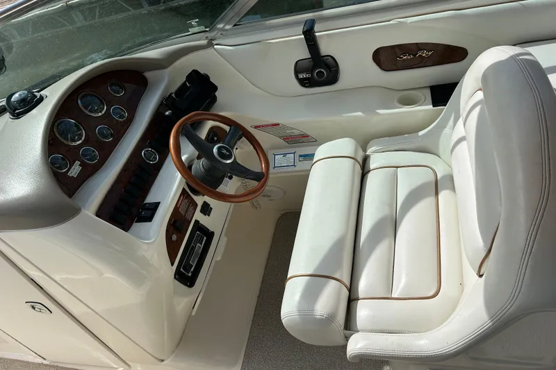 Slide: The Image of 1998 Sea Ray 280 Bow Rider cockpit with steering wheel and gauges, featuring white seating. - 70