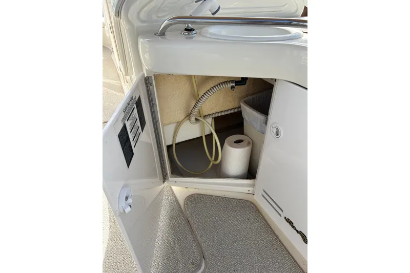 Slide: The Image of Open cabinet on 1998 Sea Ray 280 Bow Rider boat showing storage space and sink. - 78