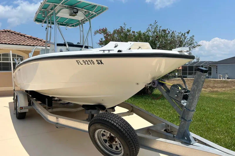 Slide: The Image of 2008 Boston Whaler 230 Dauntless boat on trailer, parked in driveway under clear sky. - 21