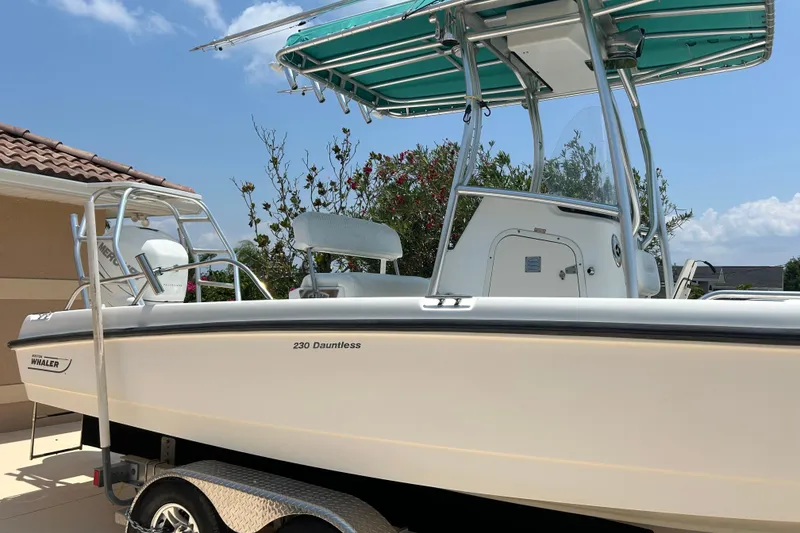 Slide: The Image of 2008 Boston Whaler 230 Dauntless boat on trailer, featuring a teal canopy. - 22