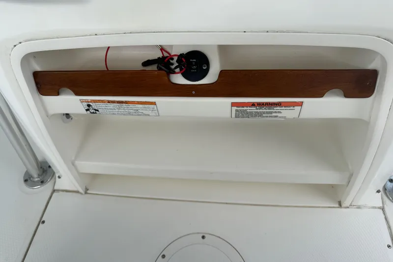 Slide: The Image of Storage compartment on a 2008 Boston Whaler 230 Dauntless boat with warning labels. - 27