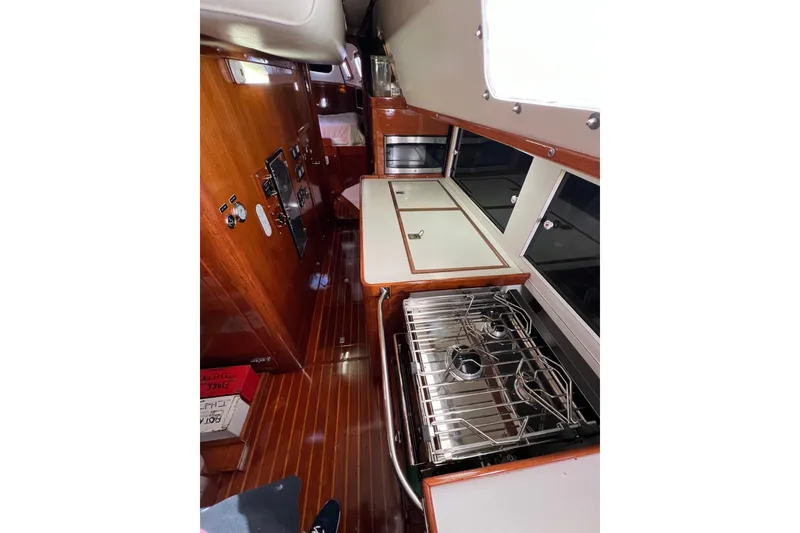 Slide: The Image of Interior of a 1978 Gulfstar Ketch yacht featuring a compact kitchen with stove and wooden cabinetry. - 34