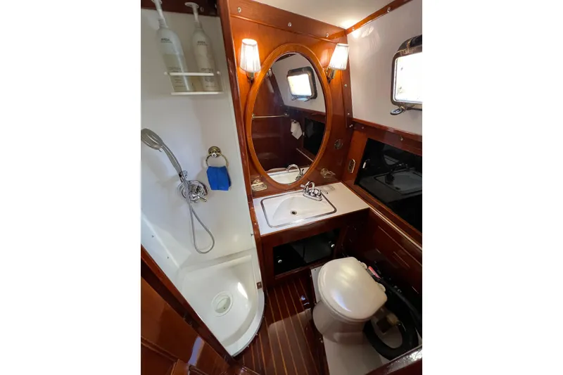 Slide: The Image of 1978 Gulfstar Ketch bathroom with wooden accents, oval mirror, and compact shower area. - 42