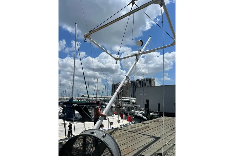 Slide: The Image of 1978 Gulfstar Ketch sailboat in marina, mast being installed under blue sky. - 7