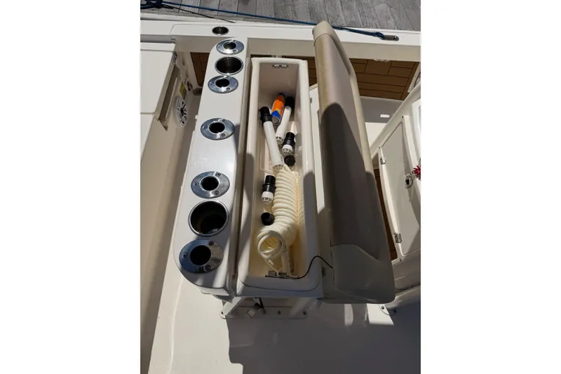 Slide: The Image of 2022 Pathfinder 2200 TRS boat storage compartment with rod holders and hose. - 34