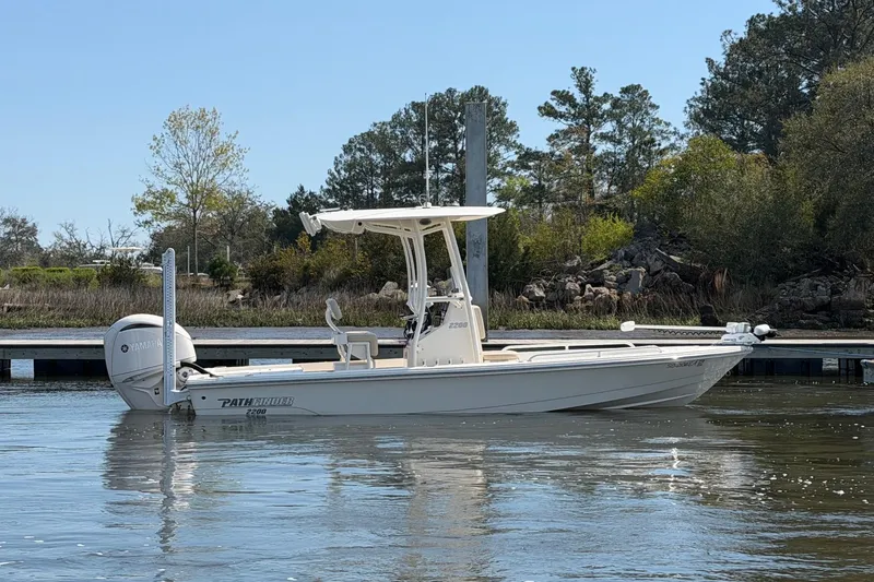 Slide: The Image of 2022 Pathfinder 2200 TRS boat on calm water, surrounded by trees and a dock. - 8