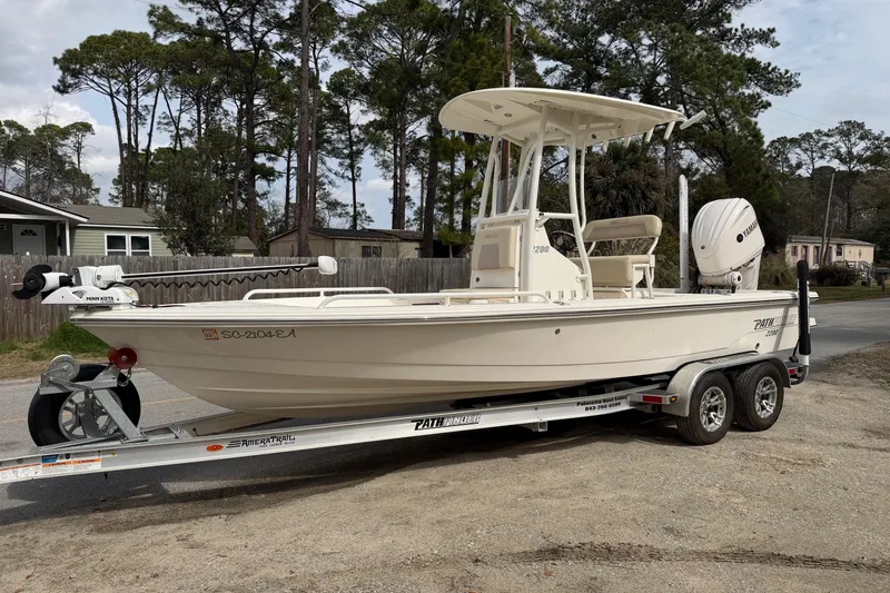 Slide: The Image of 2022 Pathfinder 2200 TRS boat on trailer, parked outdoors near trees and houses. - 9