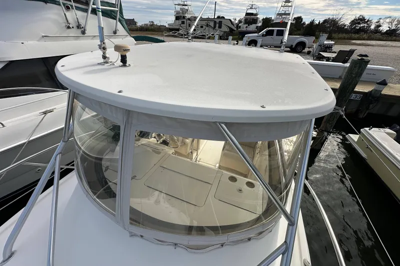Slide: The Image of 2001 Scout 280 Abaco boat docked, featuring a covered helm and clear enclosure. - 18
