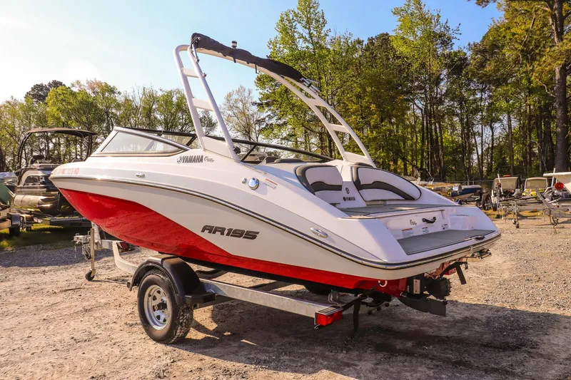 Slide: The Image of 2024 Yamaha Boats AR195 on trailer, red and white, parked outdoors. - 3