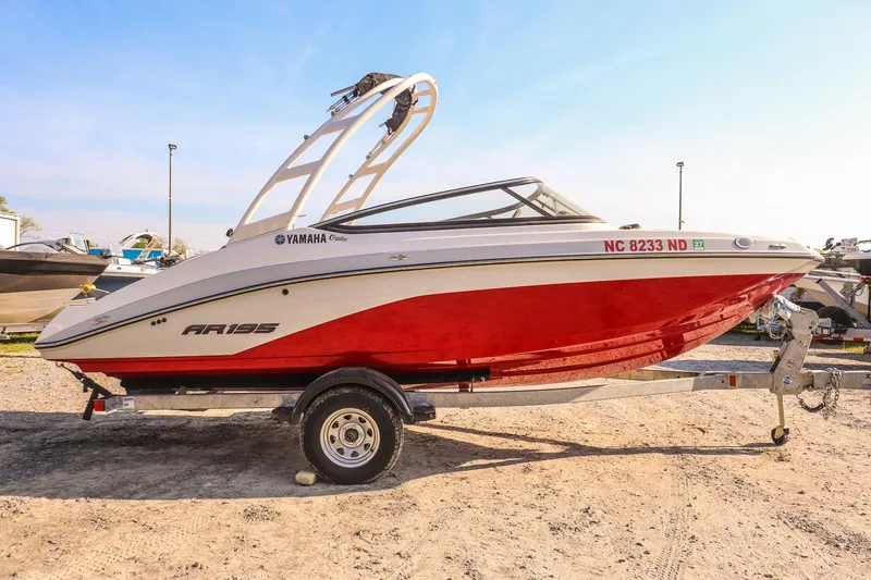 Slide: The Image of 2024 Yamaha AR195 boat with red hull on a trailer, parked outdoors. - 6