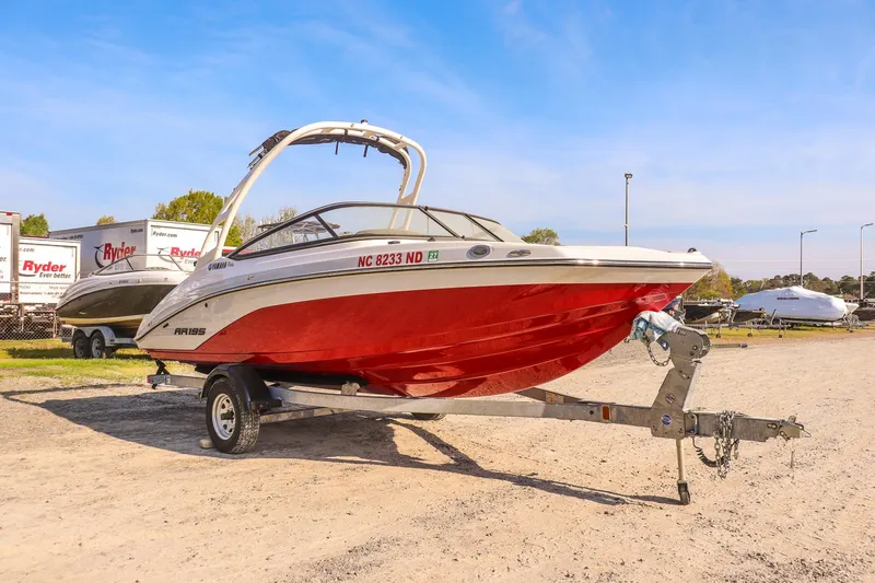Slide: The Image of 2024 Yamaha Boats AR195 with red hull on trailer in outdoor setting. - 7