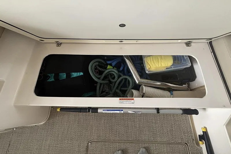 Slide: The Image of Storage compartment of a 2014 Pursuit SC 365i Sport Coupe with ropes and cleaning supplies. - 24