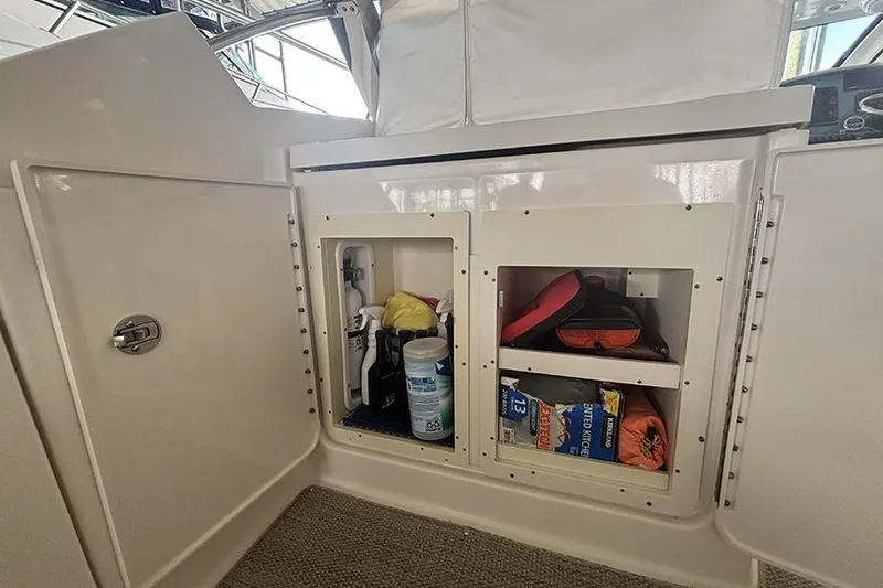 Slide: The Image of Storage compartments on a 2014 Pursuit SC 365i Sport Coupe boat, containing cleaning supplies and gear. - 34