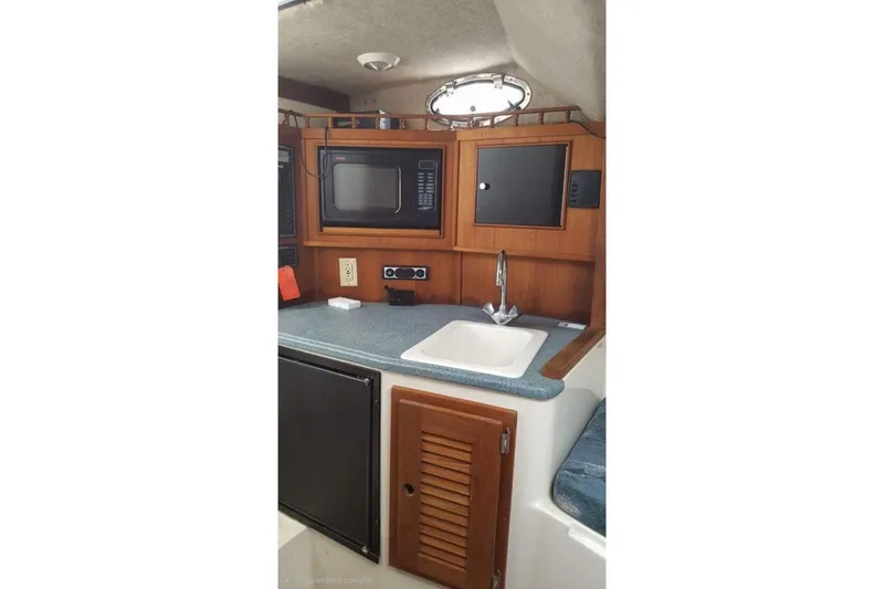 Slide: The Image of 2004 Carolina Classic 28 boat interior with kitchenette, microwave, sink, and storage cabinets. - 11