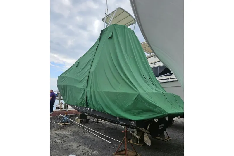 Slide: The Image of 2004 Carolina Classic 28 boat covered with a green tarp at a dock. - 13