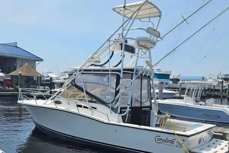 Slide: The Image of 2004 Carolina Classic 28 boat docked at marina, featuring tower and fishing equipment. - 2
