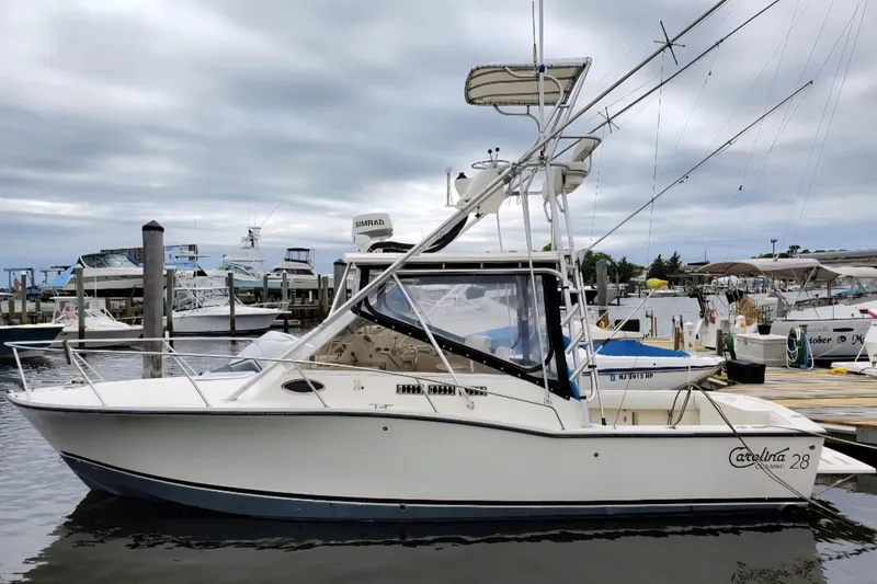Slide: The Image of 2004 Carolina Classic 28 boat docked at marina under cloudy sky. - 4