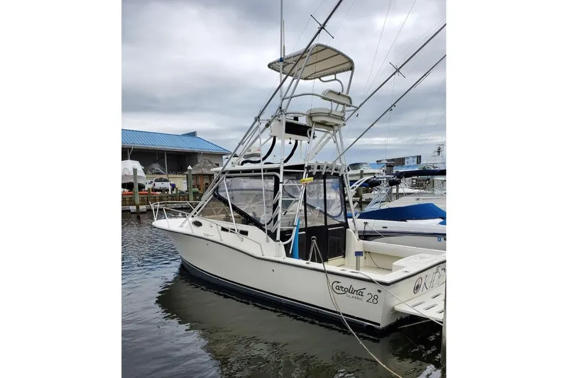 Slide: The Image of 2004 Carolina Classic 28 boat docked at marina under cloudy sky. - 5