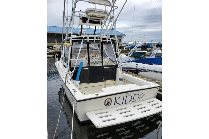 Slide: The Image of 2004 Carolina Classic 28 boat docked at marina, rear view with tower and name "KIDD". - 6