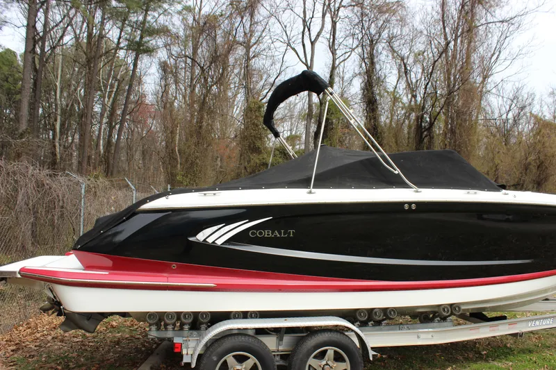 Slide: The Image of 2012 Cobalt A25 boat on trailer, covered, in wooded area. - 46