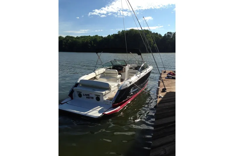 Slide: The Image of 2012 Cobalt A25 boat docked on a serene lake under a clear blue sky. - 49