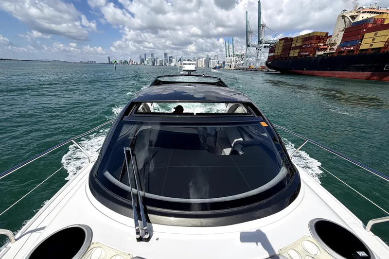 Slide: The Image of 2024 Schaefer 400 yacht cruising near city skyline and cargo ship. - 6