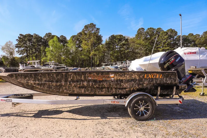 Slide: The Image of 2026 Excel 183 Tomahawk boat on trailer, parked outdoors with trees in background. - 6