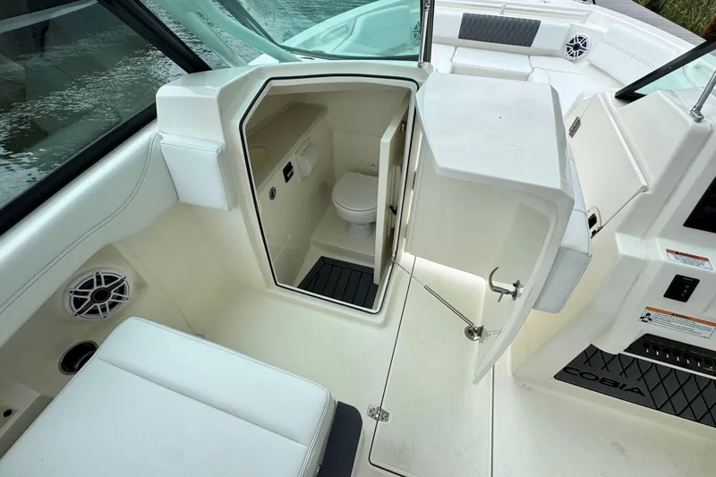 Slide: The Image of 2026 Cobia 240 Dual Console boat interior with open cabin door and visible toilet. - 15