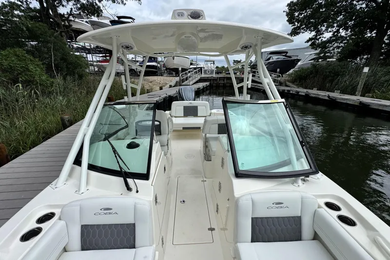 Slide: The Image of 2026 Cobia 240 Dual Console boat docked, featuring spacious seating and sleek design. - 18