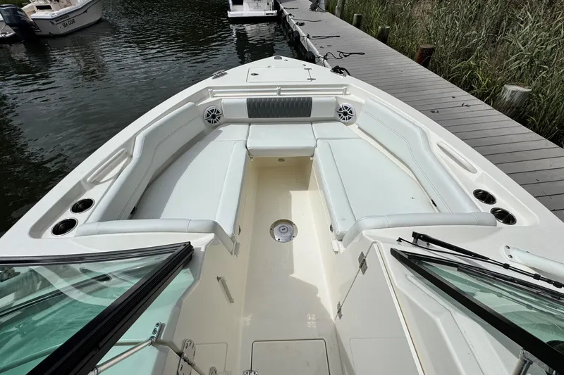 Slide: The Image of 2026 Cobia 240 Dual Console boat interior with spacious seating and cup holders, docked by the water. - 19