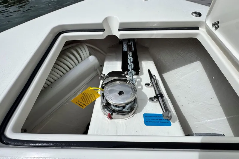 Slide: The Image of Anchor compartment of 2026 Cobia 240 Dual Console boat, featuring chain and winch. - 20