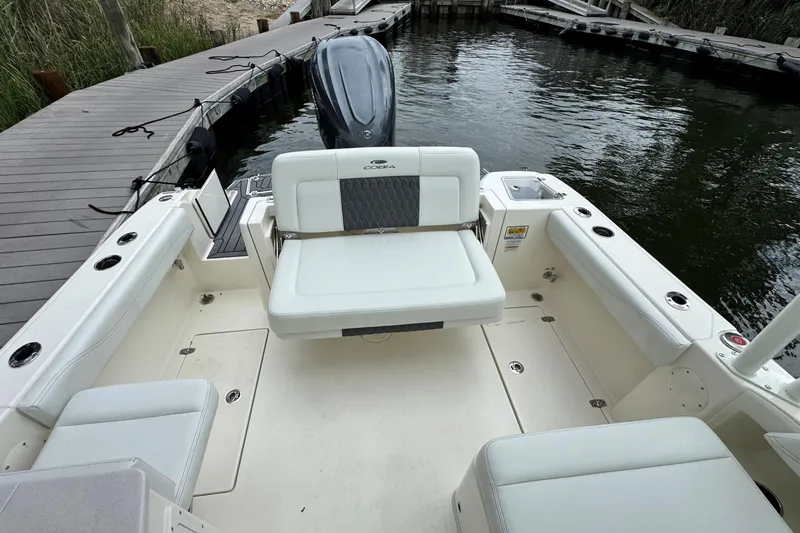 Slide: The Image of 2026 Cobia 240 Dual Console boat interior with seating, docked by the water. - 6
