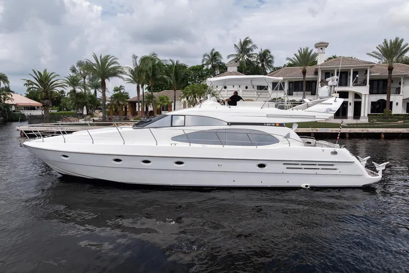 The Image of 1999 Azimut 58 yacht docked near luxury waterfront homes and palm trees. - 0
