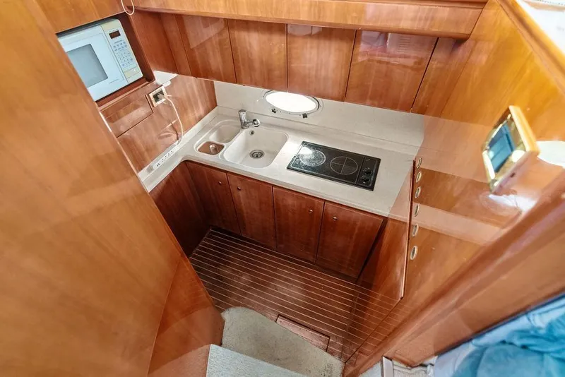 Slide: The Image of Compact kitchen in a 1999 Azimut 58 yacht with wooden cabinetry and modern appliances. - 23