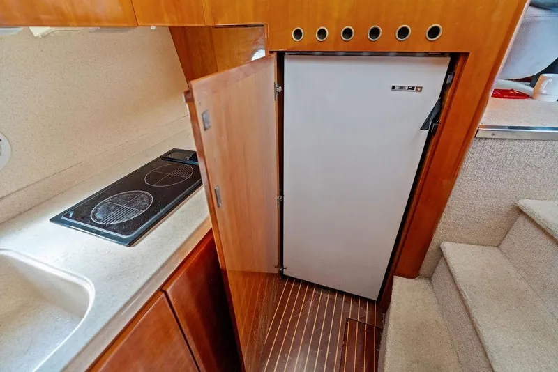 Slide: The Image of 1999 Azimut 58 yacht kitchen with stove, fridge, and wooden cabinetry. - 24