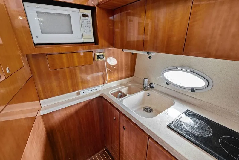 Slide: The Image of 1999 Azimut 58 yacht kitchen with microwave, sink, stovetop, and wooden cabinetry. - 25