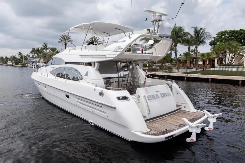 Slide: The Image of 1999 Azimut 58 yacht cruising on a calm waterway, surrounded by palm trees. - 3