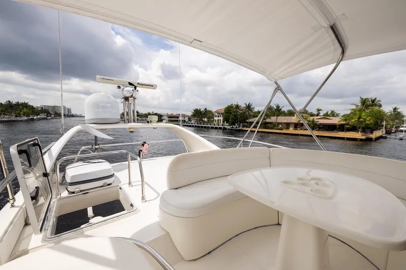 Slide: The Image of Luxurious 1999 Azimut 58 yacht interior with seating and table, overlooking waterfront homes. - 42