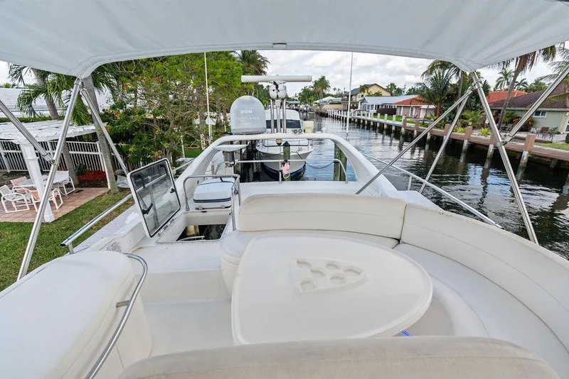 Slide: The Image of Flybridge view of 1999 Azimut 58 yacht docked by a canal with lush surroundings. - 53