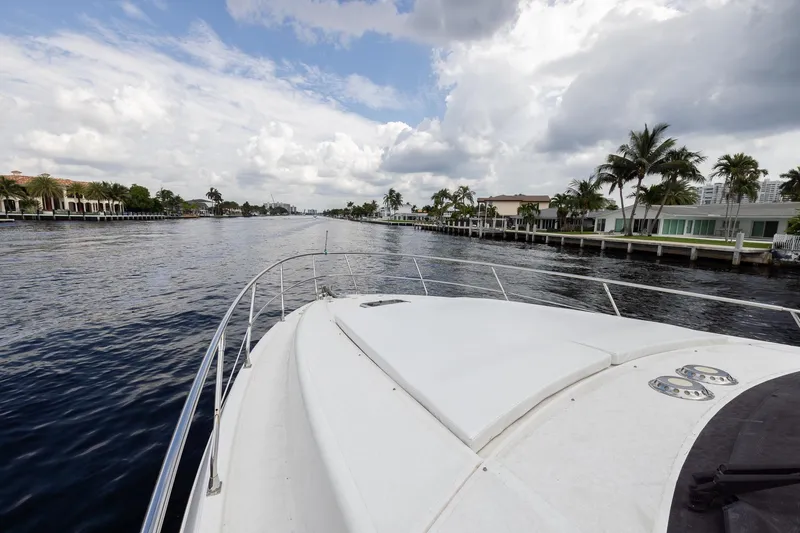 Slide: The Image of Bow view of a 1999 Azimut 58 yacht cruising along a scenic waterfront. - 6