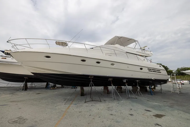 Slide: The Image of 1999 Azimut 58 yacht on dry dock, showcasing sleek design and spacious deck. - 63
