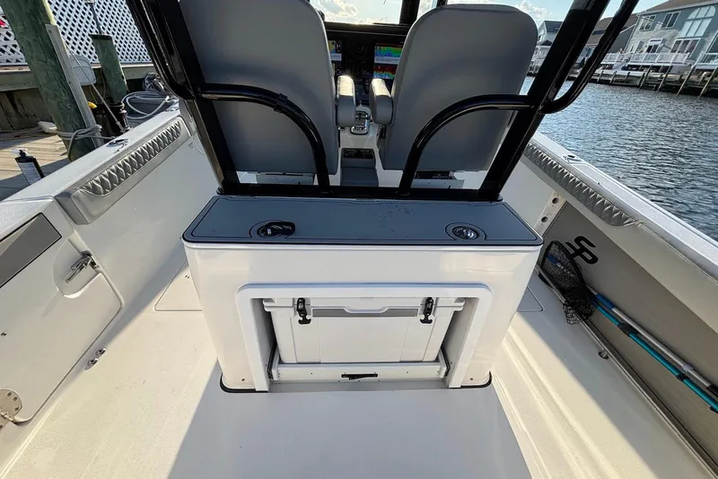 Slide: The Image of 2021 Sea Pro 320 DLX Center Console boat interior with seating and storage, dockside view. - 11
