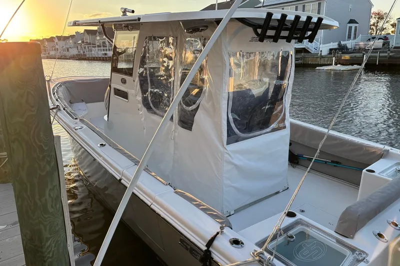 Slide: The Image of 2021 Sea Pro 320 DLX Center Console boat docked at sunset, featuring protective enclosure. - 2