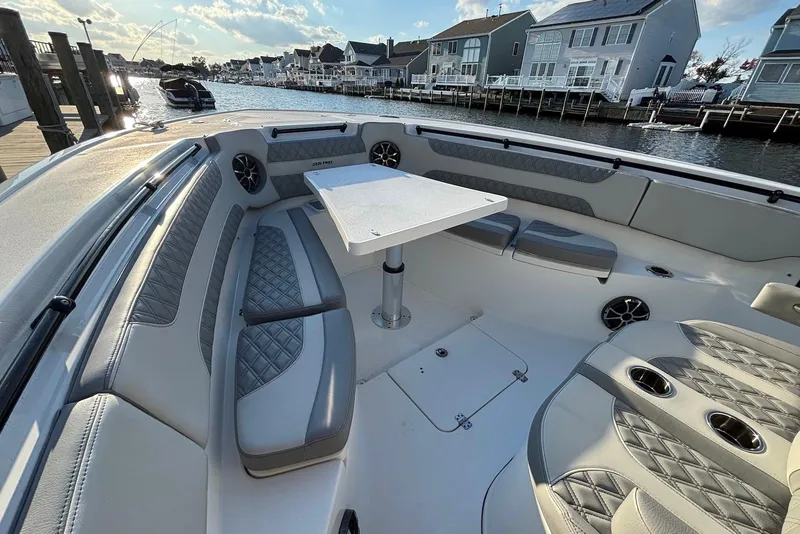 Slide: The Image of 2021 Sea Pro 320 DLX Center Console boat with luxurious seating and table, docked by waterfront homes. - 5