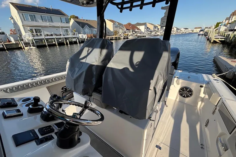 Slide: The Image of 2021 Sea Pro 320 DLX Center Console boat interior with covered seats, docked in a canal. - 8